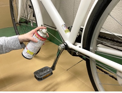 ペダル部分に自転車用潤滑剤をスプレーしているところ